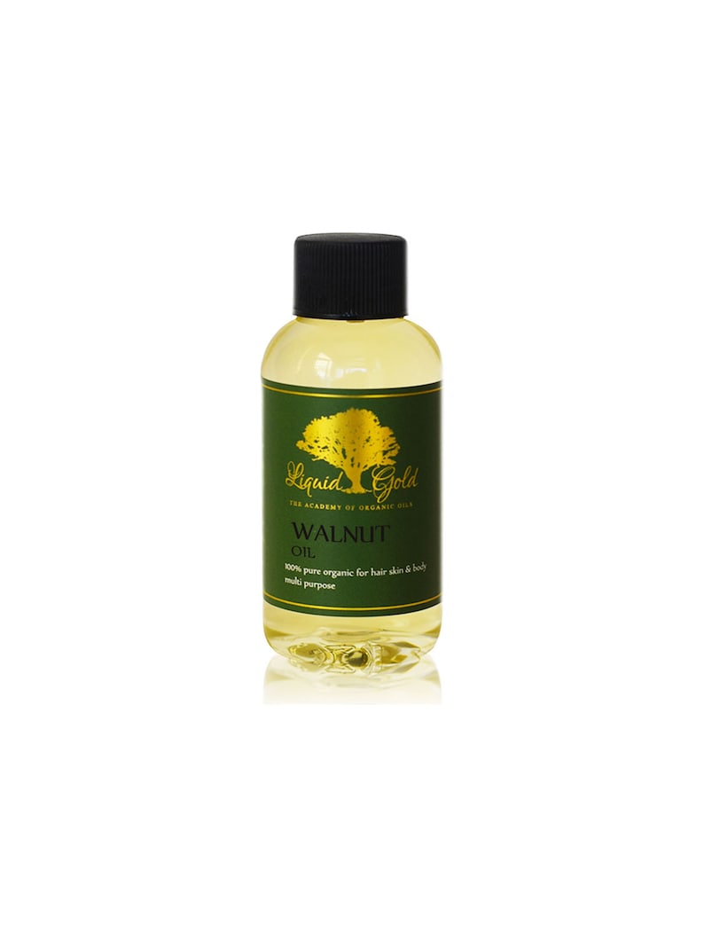 Pode incluir: Uma garrafa de vidro transparente com uma tampa preta cheia de um l&iacute;quido amarelo claro. A garrafa tem um r&oacute;tulo verde e dourado com o texto "Liquid Gold The Academy of Organic Oils Walnut Oil 100% pure organic for hair skin & body multi purpose".