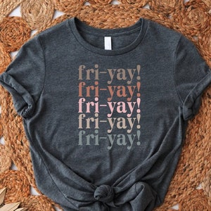 May include: A dark gray t-shirt with the text "fri-yay!" repeated five times in different shades of pink, brown, and gray.