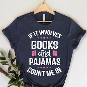 May include: A navy blue t-shirt with white text that reads "If it involves books and pajamas count me in". The text is in a distressed font and the words "books" and "pajamas" are highlighted in pink.
