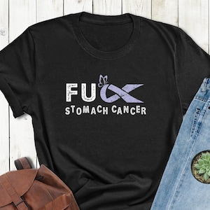 May include: Black t-shirt with the text "F**k Stomach Cancer" and a purple ribbon with a butterfly graphic.
