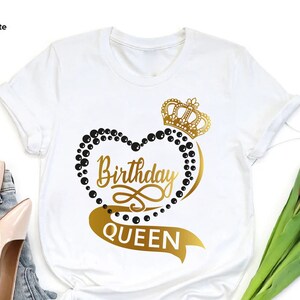 May include: White t-shirt with a gold crown and heart design. The heart is outlined with black beads and the text "Birthday Queen" is written in gold.