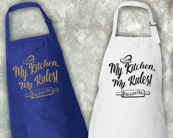 May include: Two kitchen aprons, one royal blue and one white, with the text "My Kitchen, My Rules!" and a rolling pin graphic.