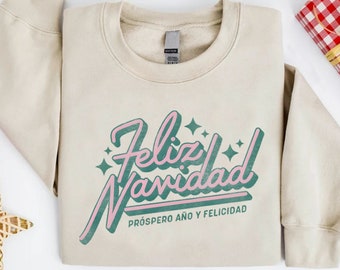 May include: A beige sweatshirt with a green and pink graphic that says "Feliz Navidad" with the text "Prospero Año y Felicidad" underneath.