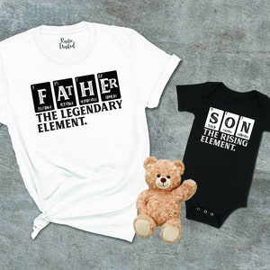 May include: White and black t-shirt with the text "FATHER THE LEGENDARY ELEMENT." and a black and white bodysuit with the text "SON THE RISING ELEMENT."