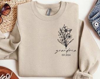 May include: A beige sweatshirt with a black floral design and the text "grandma EST. 2024".