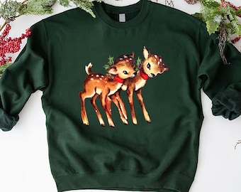 May include: A dark green sweatshirt with a vintage illustration of two deer with red bows. The deer are standing close together and have a festive feel.