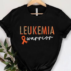 May include: Black t-shirt with the text "Leukemia warrior" in orange and white. An orange ribbon with a leopard print design is next to the text.