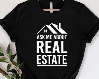 May include: Black t-shirt with white text that reads "Ask me about real estate" and a graphic of a house.