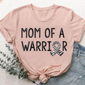 May include: A pink t-shirt with the text "MOM OF A WARRIOR" and a black and white zebra patterned ribbon.