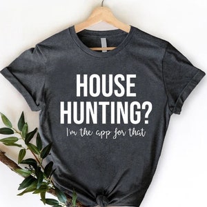 May include: A dark gray t-shirt with the text "HOUSE HUNTING? I'm the app for that" printed in white.