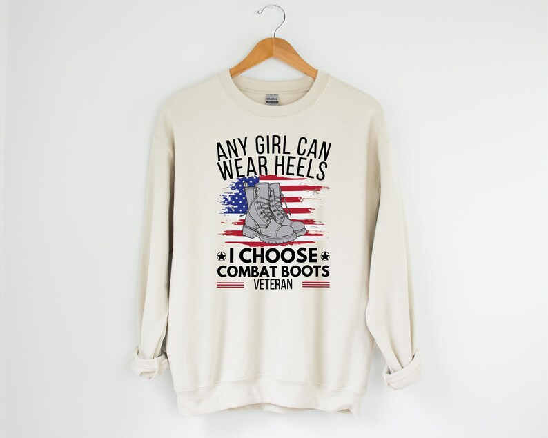 May include: A beige sweatshirt with the text "Any girl can wear heels * I choose combat boots * Veteran" and an American flag with a pair of combat boots on it.