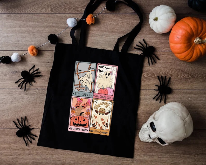 May include: Black tote bag with a Halloween theme. The bag features four illustrated cards with spooky characters and the text "The Creep", "The Ghoul Girl", "The Trick Treaters", and "The Friendly Ghost".