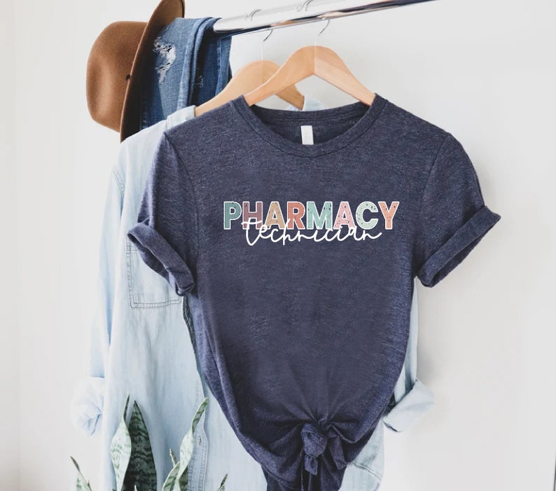 May include: A navy blue t-shirt with the text "PHARMACY Technician" in colorful letters. The letters are outlined in white and have a speckled texture.