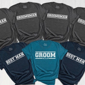 May include: A set of six t-shirts in various shades of blue and gray with white text. The shirts feature the words "Groom", "Best Man", and "Groomsman" with a date printed on the "Groom" shirt.