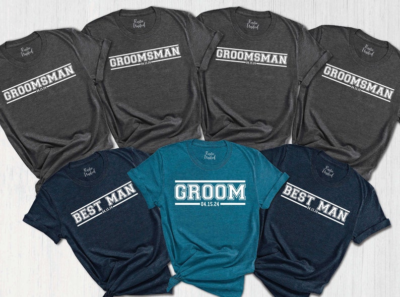 May include: A set of six t-shirts in various shades of blue and gray with white text. The shirts feature the words "Groom", "Best Man", and "Groomsman" with a date printed on the "Groom" shirt.