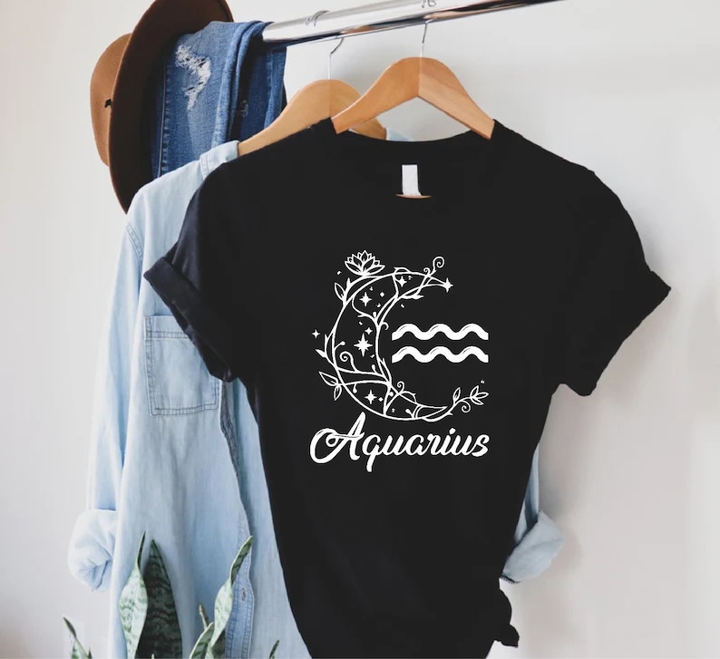 May include: Black t-shirt with a white floral design and the word "Aquarius" printed on the front.