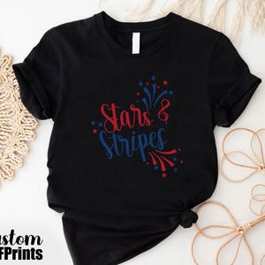 May include: Black t-shirt with red and blue text that says "Stars & Stripes" with a firework design.
