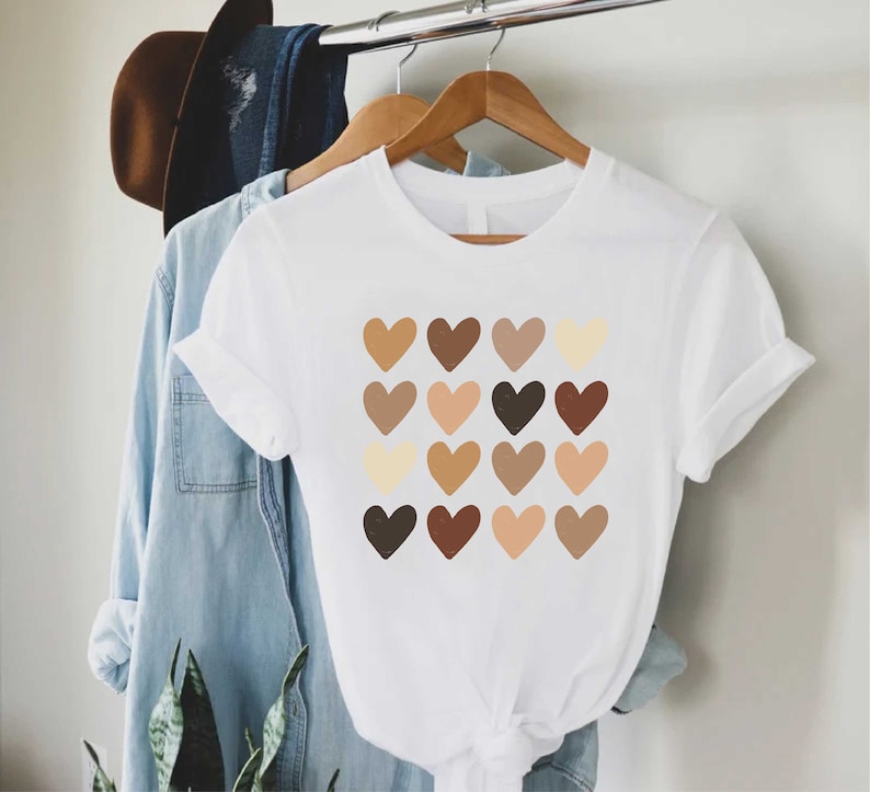 May include: White t-shirt with a graphic of a grid of 16 brown, beige, and cream hearts.