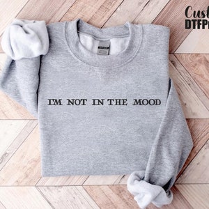 Puede incluir: Sudadera gris con el texto "I'M NOT IN THE MOOD" impreso en la parte delantera.