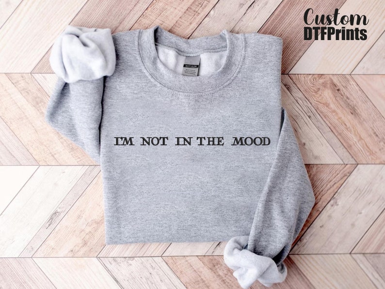 Puede incluir: Sudadera gris con el texto "I'M NOT IN THE MOOD" impreso en la parte delantera.
