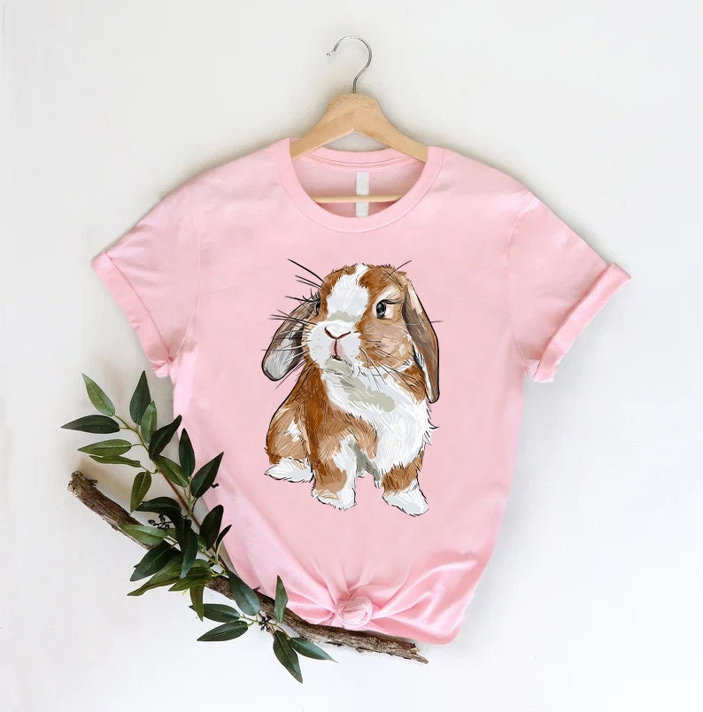 a pink shirt with a brown and white rabbit on it