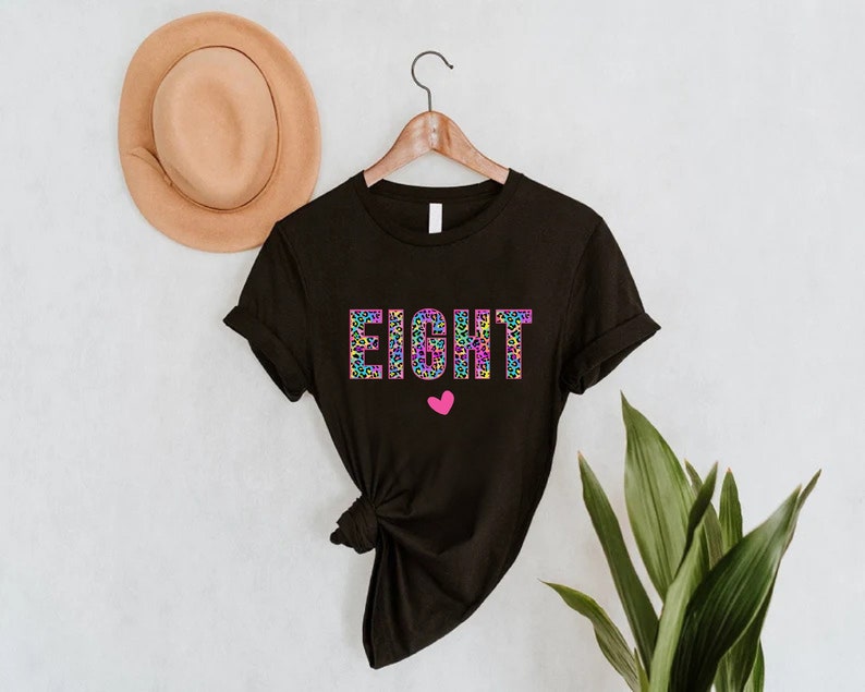 May include: Black t-shirt with the word "EIGHT" in rainbow leopard print letters and a pink heart.