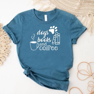Puede incluir: Una camiseta azul turquesa con un gr&aacute;fico blanco que dice "dogs books and coffee" con una huella de pata y una taza de caf&eacute;.