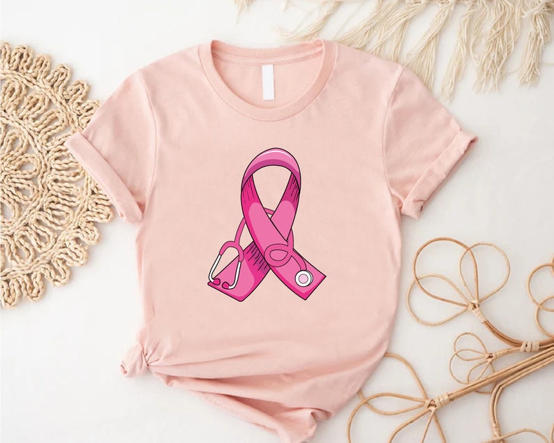 May include: Pink ribbon with a stethoscope on a light pink t-shirt.