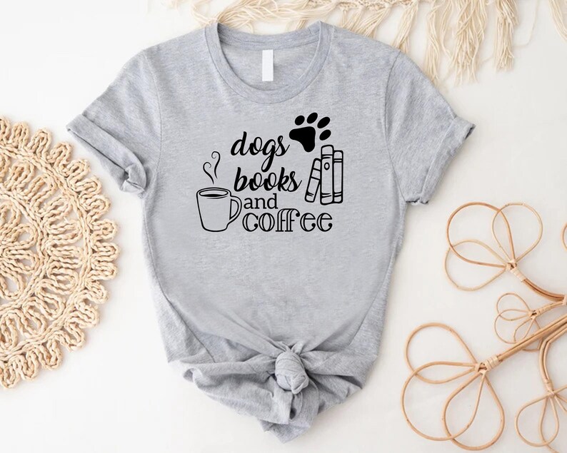 Puede incluir: Camiseta gris con una huella de pata negra y el texto "dogs books and coffee".