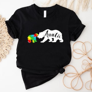 a black t - shirt with a white bear holding a puzzle piece