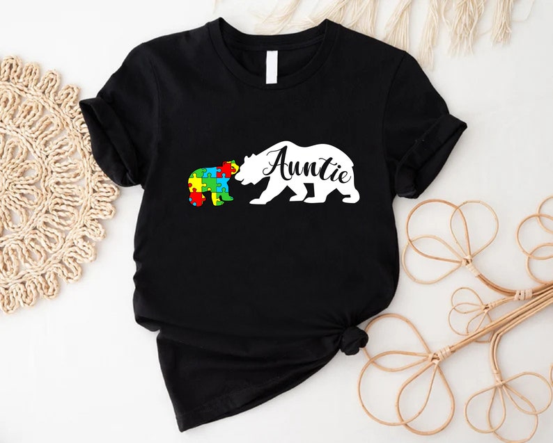 a black t - shirt with a white bear holding a puzzle piece