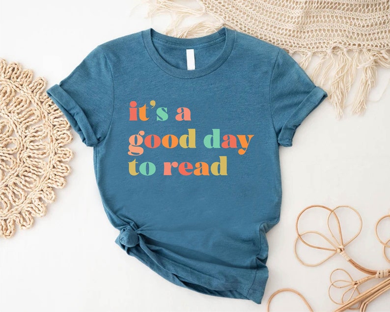 May include: A teal blue t-shirt with the text "it's a good day to read" in colourful letters.