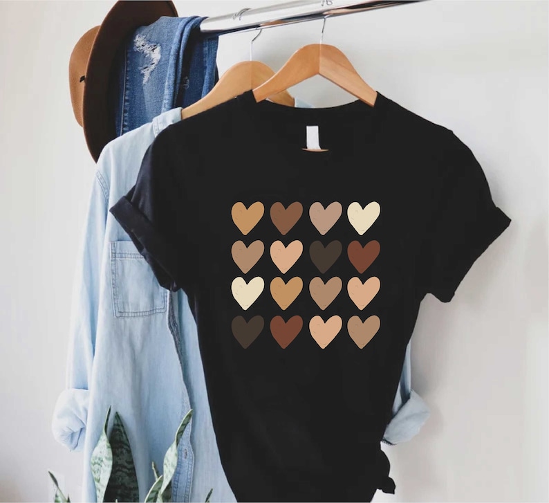 May include: Black t-shirt with a graphic of 16 hearts in different shades of brown, representing skin tones.