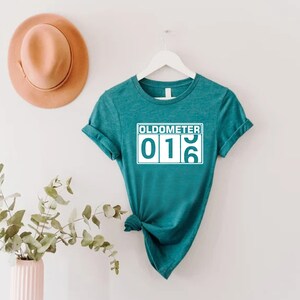 May include: Teal blue t-shirt with a white graphic that says "Oldometer 016".