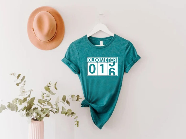 May include: Teal blue t-shirt with a white graphic that says "Oldometer 016".