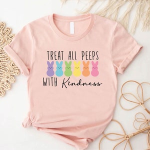 May include: Pink t-shirt with a graphic of colourful Peeps and the text "Treat all peeps with kindness."