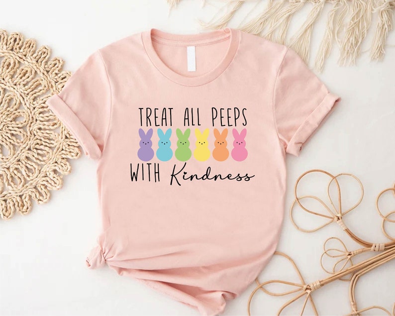May include: Pink t-shirt with a graphic of colourful Peeps and the text "Treat all peeps with kindness."