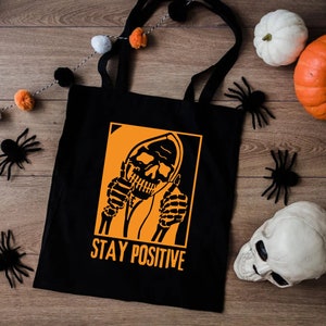 a black tote bag with a skeleton holding a cigarette