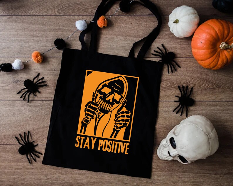 a black tote bag with a skeleton holding a cigarette