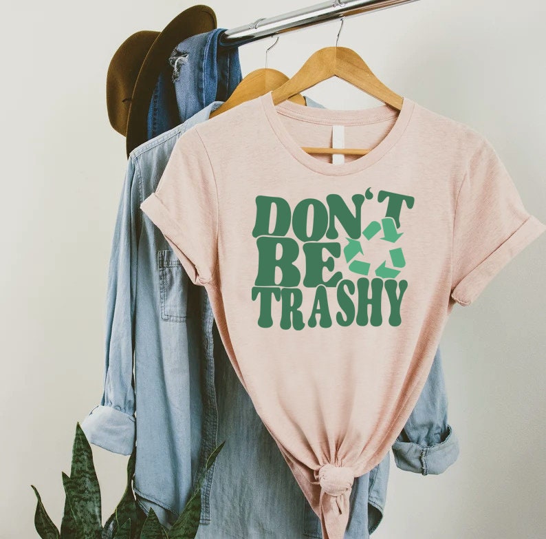 May include: A pink t-shirt with the text "Don't Be Trashy" in green letters with a green recycling symbol.
