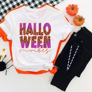 a white shirt that says hello ween on it next to a pair of black