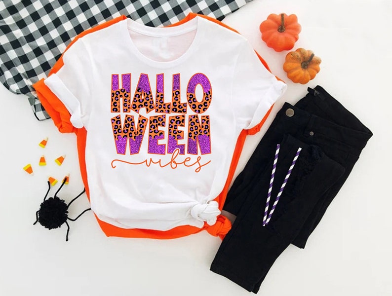 a white shirt that says hello ween on it next to a pair of black