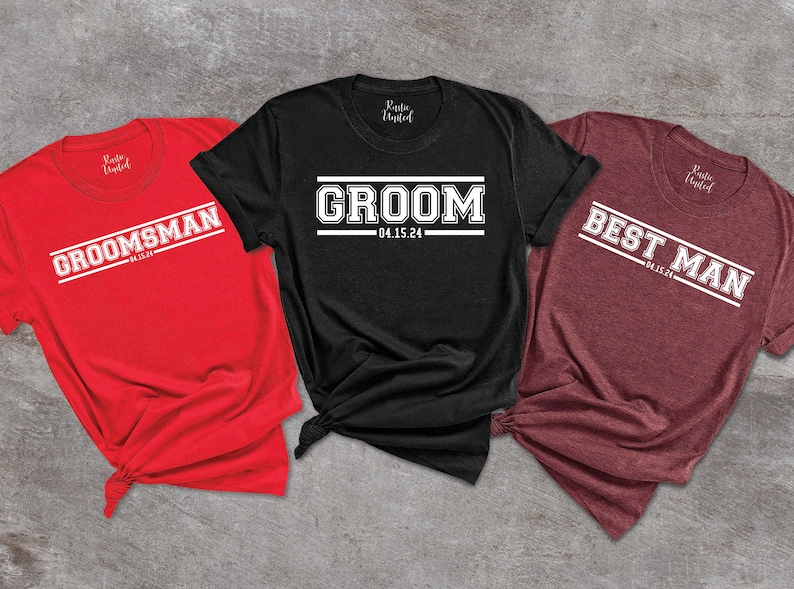 May include: Three t-shirts with a white text design on a black, red, and maroon background. The text on the shirts reads "Groom 04.15.24", "Groomsman 04.15.24", and "Best Man 04.15.24".