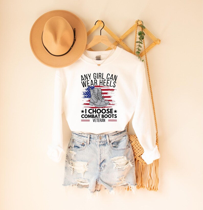 May include: White sweatshirt with the text "Any girl can wear heels *I choose combat boots* Veteran" and an American flag with a pair of combat boots on it.
