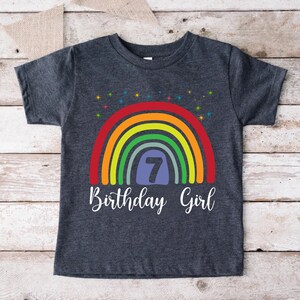 Peut inclure: Un t-shirt gris fonc&eacute; avec un motif arc-en-ciel et le texte "7 Birthday Girl".