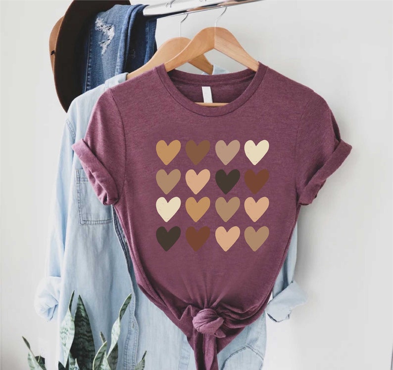 May include: A maroon t-shirt with a design of 16 hearts in different shades of brown, beige, and light brown.