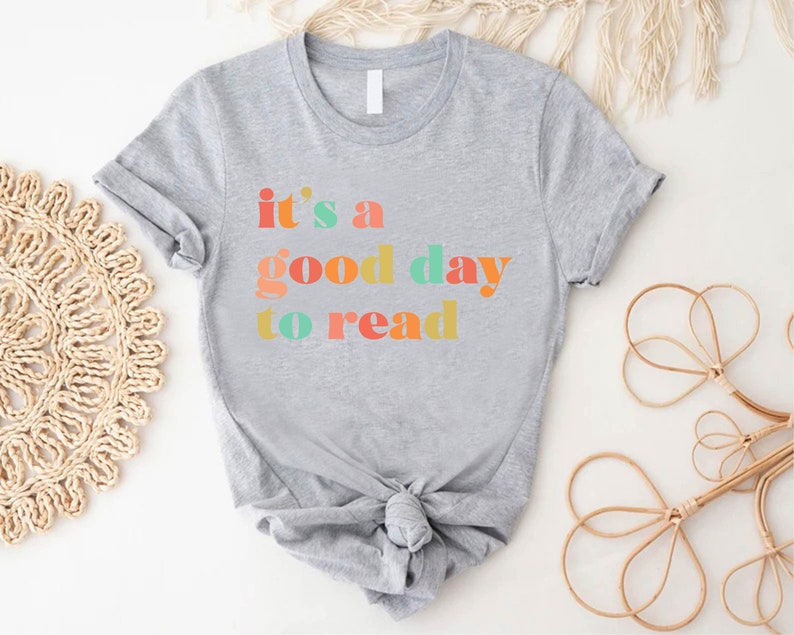 May include: Grey t-shirt with the text "it's a good day to read" in colourful letters.