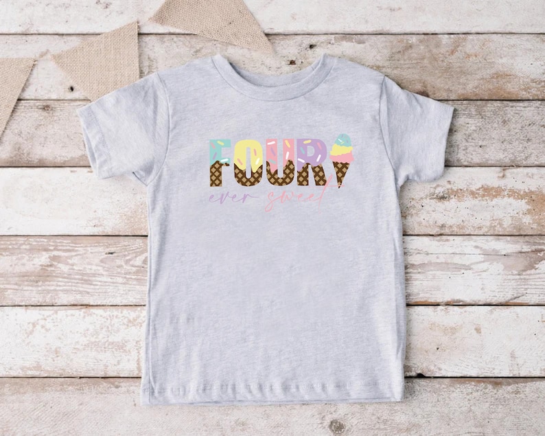 K&ouml;nnte beinhalten: Ein graues T-Shirt mit kurzen &Auml;rmeln mit dem Wort "FOUR" in bunten Buchstaben mit Eiswaffel-Designs. Der Text "ever sweet" steht unter dem Wort "FOUR".