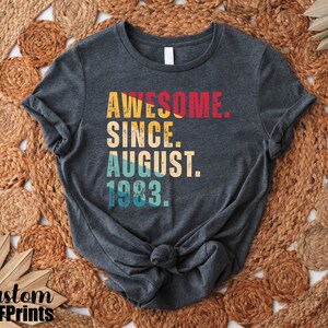 May include: A dark gray t-shirt with a vintage-style graphic that reads "Awesome Since August 1983."