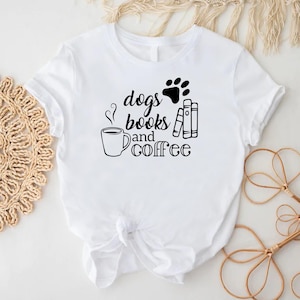 Puede incluir: Camiseta blanca con una huella de pata negra, texto que dice "dogs books and coffee" y un dibujo de una taza de caf&eacute; con vapor saliendo de ella.